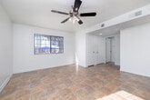 Located at 74455 Joe Davis Drive in Twentynine Palms, California, this two-story unit offers a well-organized layout designed for comfortable everyday living. The main level centers around a spacious, open living area finished with warm-toned tile flooring that runs throughout. Large windows and a sliding glass door invite abundant natural light, while ceiling fans contribute to a bright, airy atmosphere. The vaulted-style ceiling adds a sense of openness to the main living space.

The kitchen is positioned adjacent to the living area and features dark espresso-toned cabinetry, light countertops, a built-in range, range hood, and a full-size refrigerator. A peninsula counter provides a natural division between the kitchen and the main living space. Nearby, a dedicated laundry room offers built-in shelving and washer/dryer hookups for added convenience.

A carpeted staircase leads to the upper level, where bedrooms are finished with plush carpet flooring and generous wall space. Bathrooms on both levels are appointed with dark vanity cabinetry, mirrored medicine storage, tile flooring, and tub/shower combinations. The overall aesthetic throughout is clean and neutral, offering a functional and move-in ready environment.