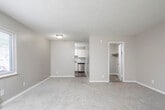 Located at 4120 Newson Rd SW in Huntsville, Alabama, this single-floor unit offers a clean, updated interior designed for comfortable everyday living. The open layout connects the main living area to the kitchen, creating a cohesive and functional flow throughout the space. Neutral gray walls, white trim, and textured ceilings provide a consistent, understated aesthetic throughout.

The kitchen is thoughtfully appointed with crisp white shaker-style cabinetry, granite-look countertops, and a full suite of stainless steel appliances, including an electric range, dishwasher, and under-cabinet range hood. Light wood-look flooring in the kitchen adds warmth and is easy to maintain.

The main living area is generously sized, bathed in natural light from a large window with exterior views, and features plush wall-to-wall carpeting. A wall-mounted HVAC unit provides climate control directly within the living space. The bedroom area is equally spacious with soft carpeting and direct access to a well-sized walk-in closet with built-in shelving and wood flooring.

A dedicated vanity area features a long countertop with built-in drawers, an expansive mirror, and wood-look flooring, offering a practical and private grooming space. Overall, the unit presents a refreshed, move-in-ready environment with modern finishes throughout.