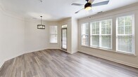 Located at 6000 Scarlet Sky Ln in Cary, NC, this well-appointed 1-bedroom, 2-bathroom residence offers a thoughtfully designed single-floor layout. The open-concept living and dining area is a standout feature, showcasing wide-plank hardwood-style flooring, crown molding, and a wall of windows that floods the space with natural light. A ceiling fan and a modern pendant light fixture add both comfort and style to this combined gathering space, which also provides direct access to a private balcony overlooking lush, mature tree canopy.

The kitchen is outfitted with gray shaker-style cabinetry, stainless steel appliances including a refrigerator, range, and over-the-range microwave, and crisp white countertops. An adjacent pantry provides additional storage convenience.

The primary bedroom is a comfortable retreat featuring hardwood-style flooring, a ceiling fan, and a window with outdoor views. The space is served by two full bathrooms — one featuring a dual-sink vanity with white countertops and matte black fixtures, and the other including a soaking tub with tiled surround. Additional highlights include a dedicated office, multiple closets, a utility room, and a separate in-unit laundry room with full-size washer and dryer. The neutral color palette and modern finishes throughout create a clean, cohesive ambiance.