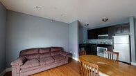 Located at 703 N Walnut in Bloomington, Indiana, this 2-bedroom, 2-bathroom unit offers a well-designed single-floor layout that maximizes functionality. The open-concept living, dining, and kitchen area serves as the heart of the home, featuring warm hardwood floors throughout and soft blue-gray walls that create a calm, cohesive atmosphere. French doors flood the space with natural light and open to a private balcony, adding an outdoor extension to the living area.

The kitchen is thoughtfully appointed with dark espresso cabinetry, a mosaic tile backsplash, dark countertops, and a full suite of stainless steel appliances including a range, microwave, and refrigerator. The seamless flow between the kitchen and dining area makes the space ideal for everyday living and entertaining.

A hallway connects the two bedrooms, each featuring hardwood floors, neutral walls, and ample closet space — three closets in total are distributed throughout the unit. The bathrooms are finished with dark slate tile flooring, a mosaic tile accent, and a shower enclosure, offering a clean and modern aesthetic. A dedicated laundry area adds everyday convenience. The overall layout is efficient and comfortable, suited for a variety of lifestyles.