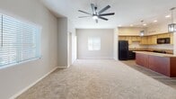 Located at 2002 E Fort Lowell Rd in Tucson, Arizona, this single-story home offers a thoughtfully designed open-concept layout that seamlessly connects the main living areas. The expansive living room features plush neutral carpeting, vaulted ceilings, recessed lighting, and a large modern ceiling fan, creating a bright and airy atmosphere. Natural light filters through multiple windows fitted with blinds, enhancing the open feel of the space.

The kitchen is a functional centerpiece, showcasing light wood upper cabinetry paired with rich cherry lower cabinets, a classic white subway tile backsplash, and granite-style countertops. A peninsula with pendant lighting provides additional prep and dining space, while black appliances including a refrigerator, range, microwave, and dishwasher complete the setup. Durable wood-look flooring runs throughout the kitchen and wet areas.

The bedrooms are carpeted and generously sized, each equipped with ceiling fans and ample natural light. The primary bathroom includes a walk-in closet with built-in shelving, a granite-top vanity with an undermount sink, and a dedicated walk-in shower. A second bathroom also features a tiled walk-in shower. A dedicated laundry closet houses a full-size side-by-side washer and dryer with overhead shelving for added convenience.
