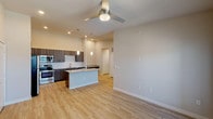 This thoughtfully designed one-bedroom, one-bathroom residence in Humble, Texas presents a contemporary open-concept floor plan that maximizes functionality and visual flow. The main living and kitchen area features light-toned wood-style flooring, neutral walls, and a ceiling fan overhead, while a door leads to an outdoor area, allowing natural light to fill the space.

The kitchen is a standout feature, showcasing dark wood-grain cabinetry that extends to the ceiling, offering generous storage capacity. Stainless steel appliances—including a refrigerator, range, and microwave—complement the granite countertops. A large center island with matching granite provides additional prep space and serves as a natural divider between the kitchen and living area. Pendant lighting and recessed fixtures add a polished touch.

The bedroom is finished with plush carpet, a ceiling fan, and a window with natural light. It connects directly to a dedicated walk-in closet and an en-suite bathroom. The bathroom features dark wood-grain cabinetry, a granite-topped vanity with an undermount sink, a soaking tub, and wood-style flooring, creating a clean and functional retreat.