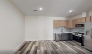 Located at 448 S Orange Ave in Newark, NJ, this thoughtfully designed one-bedroom, one-bathroom residence offers a modern living experience across a single floor. The open layout maximizes every inch of the space, with light-toned luxury vinyl plank flooring flowing consistently throughout, complemented by crisp white walls and recessed lighting that create a bright, clean aesthetic.

The kitchen is a standout feature, equipped with full-size stainless steel appliances — including a gas range, over-the-range microwave, dishwasher, and French door refrigerator. Light wood shaker-style upper cabinets are paired with charcoal lower cabinets, topped with white countertops and accented by a classic white subway tile backsplash. A matte black faucet adds a modern finishing touch.

The living area is generously proportioned, offering flexibility for various furniture arrangements, with recessed lighting overhead and easy access to closet storage via double doors with matte black hardware. The bedroom is a comfortable size, featuring a bright window that brings in natural light.

The bathroom is elegantly finished with floor-to-ceiling marble-look tile in the tub/shower surround, a white vanity with matte black fixtures, a framed mirror, and modern sconce lighting — delivering a spa-like atmosphere. This unit combines contemporary design with functional living in the heart of Newark.