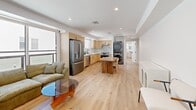 Located at 1167 W 37th Pl in Los Angeles, CA, this single-story home offers four bedrooms and three bathrooms within a thoughtfully designed open-concept floor plan. The combined kitchen and living area serves as the heart of the home, featuring light hardwood flooring throughout, recessed lighting, and generous windows that flood the space with natural light. The kitchen is outfitted with light maple cabinetry, stainless steel appliances including a French door refrigerator and dishwasher, and clean white countertops. A wooden dining table anchors the dining area, while the living room offers comfortable seating and a large sliding window with neighborhood views. An in-unit stacked washer and dryer adds everyday convenience. Each bedroom is bright and airy with large windows, light wood floors, and a clean, neutral palette. The primary bedroom provides a comfortable and well-proportioned retreat. All three bathrooms are finished with striking floor-to-ceiling marble-style tile in the walk-in showers, hexagonal mosaic tile flooring, and matte black fixtures. At least one bathroom features a sleek floating vanity with a vessel sink and a backlit mirror, elevating the modern aesthetic throughout this well-appointed Los Angeles home.