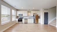 Located at 80 S 18th St. in Columbus, Ohio's vibrant 43205 corridor, this two-story residence offers a well-designed layout across two floors. The main level houses a spacious open-plan kitchen and living area bathed in natural light from multiple windows with neighborhood views. The kitchen is outfitted with white shaker-style cabinetry, a subway tile backsplash, granite countertops, stainless steel appliances including a refrigerator, range, microwave, and dishwasher, and a pendant light fixture. Light wood-tone flooring flows throughout the main level, complementing the neutral palette. A sliding barn door adds a modern industrial accent in the hallway. A full bathroom on this floor features a granite-topped vanity and wood-look flooring. Upstairs, the generously sized primary bedroom features plush carpet, tall ceilings, and a bank of windows offering views of the surrounding Columbus skyline and rooftops. A dedicated closet and a second full bathroom complete the upper level. Throughout the home, clean lines, recessed lighting, and a cohesive neutral color scheme create a bright, contemporary ambiance well-suited to modern urban living.