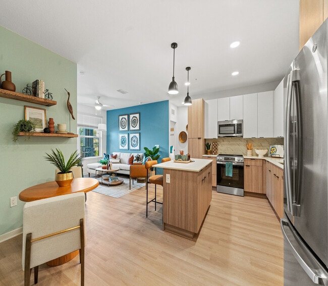 Moderno apartamento de concepto abierto que cuenta con una elegante cocina, una vibrante sala de estar con pared decorativa y una decoración elegante. - Elan Crown Point