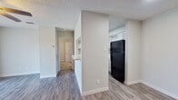 This well-designed single-floor unit offers a thoughtful layout that makes efficient use of its intimate footprint. The living room features durable wood-look flooring, a ceiling fan with light fixture, a textured ceiling, and a sliding glass door with vertical blinds that allows natural light to fill the space. Adjacent to the living area, the kitchen is accessible via a convenient pass-through counter opening, and is equipped with white cabinetry, a black refrigerator, and a sink — keeping the space functional and bright with a clean, neutral palette throughout.

A short hallway connects the main living area to the private quarters. The bedroom is carpeted for comfort and includes a ceiling fan, a window with blinds that invites natural light, and clean, neutral-toned walls. The bedroom is complemented by a generously sized walk-in closet outfitted with multiple shelving tiers and hanging rods on three walls, offering ample storage and organization options.

The full bathroom features wood-look flooring consistent with the rest of the unit, a full soaking tub with a shower and tiled surround, a toilet, and a vanity with a stone-look countertop. Throughout the unit, light gray walls and clean white trim create a cohesive, modern aesthetic that feels fresh and move-in ready.