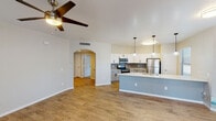 Located at 10 W Minnezona Ave in Phoenix, Arizona, this single-floor residence offers a well-designed, open-concept layout with modern finishes throughout. The living area features warm wood-look flooring, a ceiling fan with light fixture, and multiple windows that invite natural light. A built-in niche adds a subtle architectural detail, while a front entry door opens to views of the surrounding community.

The kitchen is a standout feature, centered around a large island with a light quartz countertop, an undermount sink, and a slate-blue base. White upper cabinetry contrasts with gray lower cabinets, complemented by a tile backsplash. Stainless steel appliances — including a refrigerator, electric range, and microwave — complete the functional space. Pendant lighting overhead adds a contemporary touch, and a nearby window brings in natural light.

The bedrooms are carpeted for comfort, each equipped with ceiling fans. One bedroom opens to a private balcony through a sliding glass door, offering outdoor views. A walk-in closet is accessible from one of the bedrooms. The bathroom features a vanity with a light countertop, gray cabinetry, and wood-look flooring. Arched doorways and clean white trim add architectural character throughout the home.