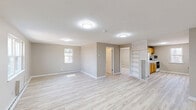 Located at 17 Regan St in Vernon Rockville, Connecticut, this one-bedroom, one-bathroom unit offers a thoughtfully laid-out single-floor plan with a clean, refreshed aesthetic throughout. Light-toned hardwood-style flooring runs continuously across every room, lending a cohesive and airy feel to the entire space.

The open living area is generously proportioned, featuring neutral warm-gray walls, bright flush-mount ceiling lighting, and baseboard heating. A built-in shelving unit adds functional storage and visual interest to the living space. Multiple windows allow natural light to filter in, enhancing the open atmosphere.

The kitchen is well-equipped with warm honey-toned wooden cabinetry, a white refrigerator, a white range with a herringbone tile backsplash, and a single-basin sink — all complemented by a window overlooking the exterior.

The bedroom is comfortably sized, offering a closet with built-in shelving, a window for natural light, and the same consistent flooring found throughout. Additional closet space is accessible from the main living area.

The bathroom is bright and clean, finished in white with a combined tub and shower, a single-sink vanity with a mirror, and a window for ventilation. Overall, this unit presents a move-in-ready, well-maintained living environment.