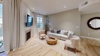 Located in the desirable 90025 zip code of Los Angeles, CA, this well-appointed 2-bedroom, 1-bathroom home offers a thoughtfully designed single-floor layout with a cohesive, contemporary aesthetic throughout. Light hardwood floors flow seamlessly across the main living areas, complementing a warm, neutral color palette of whites and earthy taupes.

The living room is a welcoming focal point, centered around a fireplace with a clean surround and flanked by black-framed windows that invite natural light. A sliding glass door opens directly to a private balcony, extending the living space outdoors. The dining area is defined by a sculptural pendant light above a round white table with bentwood chairs, and black-framed windows provide an airy, connected feel.

The kitchen features white shaker cabinetry, quartz countertops, stainless steel appliances, and a peninsula that offers additional prep and casual seating space. Built-in cabinetry in the entryway provides smart additional storage.

The spacious primary bedroom includes a distinctive taupe accent wall, recessed lighting, and direct access to the bathroom. The bathroom is finished with large-format tile floors, a glass block window for diffused natural light, a glass shower enclosure, and a floating wood vanity. A warm, artfully decorated hallway connects all rooms with understated elegance.