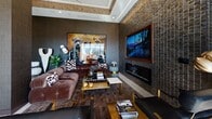 This sophisticated single-floor amenity lounge is defined by bold, contemporary interior design that blends dark textures, warm metallic accents, and eclectic artwork throughout. The space is anchored by a richly appointed lounge area featuring a plush sectional sofa, a sleek linear fireplace set into a textured dark tile wall, and a large wall-mounted display screen framed in wood — all complemented by layered rugs and curated décor including whimsical dog-themed artwork that adds a playful personality to the refined setting. An eye-catching coffered ceiling detail with warm ambient lighting and a sculptural chandelier defines the open dining and social area, which features a marble-topped table surrounded by mid-century-style chairs with black leather upholstery and brass-finished legs. Adjacent to the dining zone is a well-appointed kitchenette with dark wood cabinetry, stainless steel appliances, and a decorative wall installation of gold disc accents. The space is flooded with natural light through large, dark-framed windows that frame city views. Expansive floor-to-ceiling glass doors open directly onto a generous outdoor terrace, offering sweeping panoramic views and access to a pool deck, seamlessly extending the indoor experience to the outdoors.