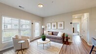 Located at 1905 Stelzer Rd in Columbus, Ohio, this 2-bedroom, 2-bathroom residence offers a thoughtfully designed single-level layout. The open-concept living and kitchen area serves as the heart of the home, where warm hardwood-style flooring flows throughout. The kitchen is equipped with sleek gray cabinetry, granite countertops, stainless steel appliances, and a peninsula island with pendant lighting and bar seating — ideal for both cooking and casual dining. The living room is bright and welcoming, benefiting from large windows with natural light and direct access to an exterior door. Two well-sized bedrooms provide comfortable retreats, each featuring plush carpet flooring and ample closet space — with four closets total throughout the unit. The primary bedroom offers a generous footprint with room for a full furniture arrangement. Both bathrooms are finished with granite vanity tops, gray cabinetry, wood-style flooring, and tub/shower combinations. Additional conveniences include a dedicated laundry room, a utility room, and a hallway connecting the private quarters. The overall aesthetic is clean and contemporary, with neutral tones throughout creating a cohesive and inviting atmosphere.
