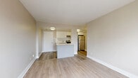 Located on Rue Sherbrooke Est in Montréal's vibrant Plateau-adjacent neighbourhood, this 2-bedroom, 1-bathroom unit offers a clean, modern aesthetic throughout. Light wood laminate flooring flows seamlessly across all rooms, complemented by neutral warm-beige walls and crisp white trim that create a bright, cohesive atmosphere.

The kitchen is a standout feature, equipped with stainless steel appliances including a full-size refrigerator, electric range, and dishwasher. White flat-panel cabinetry, a subway tile backsplash, and a generous central island with a white countertop provide ample workspace and add a contemporary touch. The kitchen opens directly to the living area, creating a practical and social layout.

The spacious primary bedroom benefits from a large window framing views of the Montréal skyline and Mount Royal in the distance, with baseboard heating units running along the exterior wall. The second bedroom is well-proportioned, featuring a double-door closet and the same light flooring found throughout.

The bathroom is neatly appointed with large-format white floor tiles, a dark-toned vanity with a white countertop, a wall-mounted mirror, and a tiled tub-shower combination. Overall, the unit presents a well-maintained, move-in-ready space with a clean, functional design suited to urban living in Montréal.