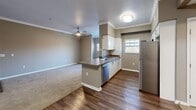 Located at 2100 W Texas St in Fairfield, CA, this well-appointed one-bedroom, one-bathroom residence offers a thoughtfully designed single-floor layout. The open-concept living and dining area is finished with warm neutral tones, plush carpeting, and crown molding, creating a comfortable and cohesive atmosphere. A ceiling fan provides added comfort in the living space, which connects seamlessly to a private balcony with sliding glass door access.

The kitchen is a functional highlight, featuring white cabinetry, dark countertops, stainless steel appliances — including a refrigerator, range, microwave, and dishwasher — and rich wood-look flooring. A peninsula counter separates the kitchen from the living and dining area, making it ideal for both cooking and entertaining.

The bedroom is carpeted and filled with natural light from a window with blinds, offering a quiet retreat. Three closets throughout the unit — including a spacious walk-in with wire shelving — provide generous storage options. An in-unit laundry area adds everyday convenience.

The bathroom features a full tub and shower combination, a white vanity with ample cabinet storage, a large mirror, and wood-look flooring, completing this practical and well-finished residence.
