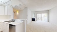 Located at 7077 Alvern St in Los Angeles, CA, this 2-bedroom, 1-bathroom residence offers a well-organized single-floor layout with a bright, neutral palette throughout. The open-concept living and dining area is anchored by a fireplace and features plush carpeting, a large mirror wall, and sliding glass doors that lead to a private balcony, filling the space with natural light. The kitchen is efficiently designed in an L-shape configuration with white cabinetry, white countertops, light wood-style flooring, a stainless steel dishwasher, and a gas range beneath a panel-lit ceiling. The generously sized primary bedroom offers ample room and is complemented by dual sliding-door closets with built-in shelving. The second bedroom also features carpeted floors, a walk-in closet, and a bright window. The shared bathroom includes a full tub-shower combo, wood-style flooring, and clean white fixtures. A dual-sink vanity with a large mirror is conveniently situated adjacent to the primary bedroom. Throughout, the space maintains a clean, light-toned aesthetic with textured ceilings, making it a functional and comfortable residence in the heart of Los Angeles.