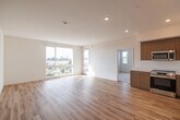 Located in San Diego's Mission Village neighborhood, this thoughtfully designed 2-bedroom, 2-bathroom residence offers a clean, modern aesthetic throughout. The open-concept layout seamlessly connects the living room and kitchen, both finished with light hardwood-style flooring that enhances the bright, airy atmosphere. Large windows and a glass door open to a private balcony, flooding the living area with natural light and offering expansive views of the surrounding San Diego skyline and treetops.

The kitchen is well-appointed with flat-front wood-toned cabinetry, white quartz countertops, a clean white tile backsplash, and a full suite of stainless steel appliances including a range, dishwasher, microwave, and refrigerator. Recessed lighting adds a polished finishing touch.

Both bedrooms feature plush carpeting, crisp white walls, and large sliding windows that frame scenic outdoor views. The spacious primary bedroom offers generous proportions, while the secondary bedroom includes a wide sliding-door closet for ample storage.

The two bathrooms are finished with hardwood-style flooring, warm wood-toned vanity cabinetry, white countertops, and a tiled tub/shower combination. Clean lines and a neutral palette create a cohesive, contemporary feel throughout this well-designed San Diego residence.