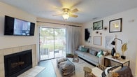 This single-floor residence offers a thoughtfully designed layout that balances comfort and functionality across its key living spaces. The living room serves as the heart of the home, anchored by a tile-surround fireplace and a ceiling fan overhead. A sliding glass door opens to an outdoor patio, flooding the room with natural light and providing pleasant views of the surrounding greenery. Wood-style flooring runs throughout the main living areas, adding warmth and cohesion to the space.

Adjacent to the living room, the dining area features a pass-through window connecting directly to the kitchen, enhancing the open feel. An elegant chandelier adds a refined touch to the dining space. The galley-style kitchen is equipped with stainless steel appliances, white cabinetry, dark countertops, and durable wood-look flooring, offering both practicality and style.

The two bedrooms are carpeted for comfort. The primary bedroom includes a walk-in closet and a window that brings in natural light. Both bathrooms feature white vanity cabinetry with dark countertops, wood-style flooring, and tub-shower combinations, presenting a clean and consistent aesthetic throughout. The overall ambiance of the residence is bright, modern, and inviting.