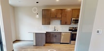 This contemporary 1-bedroom apartment in Madison, WI, maximizes its 440 square feet with a thoughtful, open-concept design. The heart of the home is a sleek kitchen, boasting wood-grain cabinetry, stainless steel appliances, and a subway tile backsplash. The kitchen seamlessly flows into a living area, characterized by warm wood flooring and ample natural light.

The bedroom, measuring 100 square feet, offers a cozy retreat with built-in storage solutions, including a custom closet system with drawers and shelving. The bathroom features a modern vanity with a quartz countertop and undermount sink, complemented by a large framed mirror.

Throughout the apartment, neutral tones create a calming atmosphere, while the wood elements add warmth and texture. The efficient layout includes clever storage solutions, ensuring every square foot is utilized effectively. High ceilings and recessed lighting contribute to the spacious feel of this compact yet stylish urban dwelling.