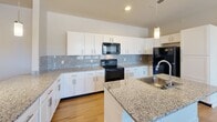 Located at 2139 Topside Rd in Alcoa, Tennessee, this well-appointed 3-bedroom, 3-bathroom residence offers a thoughtfully designed single-floor layout. The open-concept living area seamlessly integrates the kitchen, dining, and living spaces, creating a bright and functional hub for daily living. The kitchen is a standout feature, showcasing granite countertops, white shaker cabinetry, a subway tile backsplash, black appliances, and a central island with a stainless steel sink — all illuminated by pendant lighting. Warm light wood flooring runs throughout the home, complementing the clean, neutral color palette. Each of the three bedrooms is generously proportioned, with ceiling fans, large windows that invite natural light, and access to dedicated closets. The primary bedroom includes its own bathroom and a walk-in closet with built-in wire shelving. The primary bathroom features a dual-sink granite vanity, large mirrors, and a soaking tub. A dedicated laundry room and utility space add everyday convenience. The home also includes a private balcony with open views of the surrounding landscape. With six closets providing ample storage and a clean, modern aesthetic throughout, this residence offers a comfortable and practical living environment.