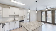 Located at 1000 Ashwood Pkwy in Atlanta, Georgia, this well-appointed single-floor residence combines modern design with functional living. The open-concept layout connects the kitchen and living areas seamlessly, creating a bright and inviting atmosphere throughout.

The kitchen is a standout feature, showcasing white shaker-style cabinetry with matte black hardware, granite countertops, a classic subway tile backsplash, and a central island with pendant lighting overhead. Stainless steel appliances complete the space, making it as practical as it is attractive.

The living area benefits from large glass French doors that invite generous natural light and provide outdoor access, complemented by light hardwood-style flooring and a ceiling fan. Stylish raised panel interior doors in a warm gray tone add a cohesive design element throughout the unit.

The bedrooms feature plush carpeting and ample closet space, offering a comfortable retreat. The bathrooms are finished with granite-topped white vanities, matte black fixtures, large mirrors, and wood-look flooring, maintaining the consistent modern aesthetic found throughout the residence.

Overall, this space presents a clean, contemporary design with quality finishes, an abundance of natural light, and a well-planned layout that offers both comfort and style in the heart of Atlanta.