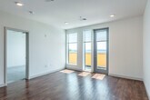 Located at 309 S Blount St in Madison, WI, this modern 1-bedroom, 1-bathroom unit offers a well-designed layout across a single floor with approximately 860 square feet of living space. A clean, light-filled hallway with hardwood flooring and recessed lighting leads into the open-concept kitchen and living area. The kitchen is outfitted with dark cabinetry, granite countertops, stainless steel appliances including a refrigerator, stove, and microwave, and a central island with a undermount sink and pendant lighting above. The living area extends naturally from the kitchen, featuring warm hardwood floors and large windows that allow abundant natural light to fill the space. The bedroom is comfortably sized with plush carpet flooring, a ceiling fan, and a large window offering natural light. It includes access to a walk-in closet with built-in wire shelving. The full bathroom features a combined tub and shower, dark vanity cabinetry, and tile flooring. Additional highlights include two closets, a dedicated laundry area, a utility room, and a private patio. The overall aesthetic is clean and contemporary, with neutral tones and modern finishes throughout.
