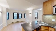 Located at 1400 North Lake Shore Drive in Chicago's prestigious Gold Coast neighborhood, this one-bedroom, one-bathroom residence offers a well-designed layout with light hardwood flooring throughout. The open living room is bathed in natural light from multiple large windows framing elevated city views, and is accented by sleek wall sconces that lend a modern, polished ambiance. The space flows seamlessly from the living area into the kitchen, which is appointed with warm honey-toned wood cabinetry, dark granite countertops, a mosaic tile backsplash, and a full suite of stainless steel appliances including a gas range, microwave, and refrigerator. The bedroom offers a comfortable footprint with its own windows showcasing skyline views, a ceiling fan, and baseboard heating. Clean white walls and light wood floors keep the room feeling bright and airy. The bathroom features full ceramic tile surrounding a soaking tub and shower combination, a white vanity with brushed nickel fixtures, and a medicine cabinet with mirror. Throughout the residence, light hardwood flooring, neutral cream walls, and abundant natural light from city-facing windows create a cohesive, inviting atmosphere ideal for urban living.