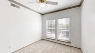 This 2-bedroom, 1-bathroom residence is thoughtfully organized on a single floor, making efficient use of its compact footprint. The living area features soft carpeting, crisp white walls, and crown molding details that lend a clean, classic aesthetic. A ceiling fan provides both lighting and airflow, contributing to everyday comfort. The kitchen is outfitted with wood-look flooring, white cabinetry, a stainless steel refrigerator, an electric range, and an overhead microwave, offering all essential appliances in a practical, well-arranged space. A stainless steel sink with a speckled countertop completes the kitchen's functional design. The primary bedroom is generously proportioned for the overall scale of the unit, featuring carpet flooring, a ceiling fan, crown molding, and dual windows with blinds that allow natural light to filter in. It also includes a closet and in-unit stacked washer and dryer hookups, adding notable convenience. The second bedroom is carpeted and well-lit, with a sliding mirrored closet door. The bathroom includes a vanity with a speckled countertop, an undermount sink, and a lighted mirror. Throughout the residence, the neutral color palette and consistent finishes create a cohesive, move-in-ready environment.
