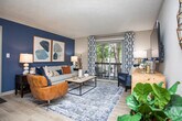 This single-story residence in Smyrna, Georgia, presents a well-organized layout with distinct living, dining, kitchen, and sleeping areas flowing seamlessly throughout. Light wood-style flooring runs continuously across the space, contributing to a cohesive and contemporary aesthetic.

The living room serves as the central gathering space, highlighted by a sliding glass door that opens to a private balcony overlooking lush greenery. A bold accent wall in deep blue anchors the room, complemented by neutral tones and ample natural light.

The open sightline connects the living area to a dedicated dining space and a galley-style kitchen. The kitchen features white shaker cabinetry, granite-style countertops, a subway tile backsplash, and stainless steel appliances, offering a clean and functional workspace.

Multiple bedrooms provide comfortable retreats, each finished with ceiling fans, light-toned walls, and large windows that invite natural light. The primary bedroom showcases a soft blue accent wall, while additional bedrooms maintain a neutral, versatile palette with ample storage space.

The bathroom includes a granite-topped vanity, a large mirror, and brushed nickel fixtures, delivering a polished, functional finish. Throughout, the space balances contemporary design with everyday practicality.