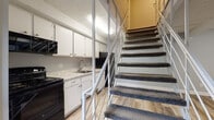 Located at 4365 Bayshire Rd in Groveport, Ohio, this two-floor residence offers a practical and well-organized layout across both levels. The main level welcomes you through a front entry door into an open living area finished with durable wood-look luxury vinyl plank flooring and soft gray walls throughout. The kitchen is positioned alongside the staircase and features white cabinetry, light granite-style countertops, a stainless steel sink, and black appliances including a range and microwave. A striking white metal open-railing staircase serves as a central architectural element, connecting both floors with an airy, modern feel. An additional room on the main level provides flexible living or flex space, also finished with LVP flooring and a window for natural light, complemented by exposed ceiling beams adding character. The upper level transitions to plush carpeting and includes a spacious bedroom with a ceiling fan, a window with blinds, and a textured ceiling. A full bathroom on this level is outfitted with a tub-shower combination, a white vanity with storage, and tile flooring. A dedicated laundry area with a washer and dryer and wire shelving, alongside a water heater, rounds out the upper level's utility. A walk-in closet provides ample storage.
