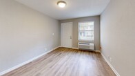 Located at 2265 Perry Blvd NW in Atlanta, GA, this one-bedroom, one-bathroom unit offers a well-organized layout across a single floor. The living room features light wood-style flooring, neutral gray walls, and a window that brings in natural light, creating a welcoming and open feel. A hallway connects the main living areas, adding to the logical flow of the space. The kitchen is efficiently designed with gray cabinetry, light granite-style countertops, a black appliance suite including an electric range and dishwasher, and a deep sink with a modern faucet. Light wood-style flooring continues here, and a rear door provides direct outdoor access. The bedroom is carpeted for added comfort and includes a ceiling fan with light fixture, a window with natural light, and built-in shelving for storage. A second window and open shelving nook are also present, adding versatile storage options. The bathroom features full white tile surrounding a soaking tub and shower combination, with a window above for ventilation and light. Clean white finishes throughout give the bathroom a crisp, functional appearance. The space as a whole maintains a consistent neutral palette, making it move-in ready and easy to personalize.