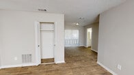 This single-floor unit offers a practical and comfortable layout designed for everyday living. The interior is finished with warm wood-look flooring throughout the main living and bedroom areas, while at least one room features plush wall-to-wall carpeting, adding a cozy touch underfoot. Neutral, warm-toned walls and white baseboards create a clean, cohesive aesthetic throughout.

The living area is open and well-lit, benefiting from natural light streaming through a large window with blinds, and features vertical blinds over a sliding glass door that opens to the exterior. A built-in closet with bifold doors provides convenient storage directly off the living space.

The kitchen is equipped with white cabinetry, light granite-style countertops, a speckled tile backsplash, and a black electric range with an overhead exhaust hood, offering a functional cooking environment.

The bathroom includes a white vanity with a granite-style countertop, a tiled tub and shower surround, and wood-look flooring, with a window providing ventilation and natural light.

Textured popcorn ceilings are consistent throughout the space, and multiple rooms feature windows that invite natural light. The overall layout, as seen in the dollhouse view, is compact yet efficiently organized to maximize usability.