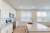 Located at 380 Crown Dr in Emerson, GA, this single-story, 2-bedroom, 2-bathroom home offers a thoughtfully designed layout with modern finishes throughout. The open-concept kitchen and living area serves as the heart of the home, showcasing crisp white cabinetry, a subway tile backsplash, granite countertops, a central island with an undermount sink, and a full suite of stainless steel appliances. Large windows with blinds fill the space with abundant natural light, creating a bright and welcoming atmosphere. Light-toned hardwood-style flooring runs throughout the main living areas, lending a clean and contemporary feel. The two bedrooms offer comfortable retreats, with plush carpeting underfoot and windows that bring in additional natural light. The primary bedroom includes a walk-in closet with wire shelving for organized storage. Both bathrooms are finished with granite-topped vanities, white cabinetry, and tiled tub-shower combinations. A dedicated closet provides additional storage. The home's neutral color palette and modern design elements create a cohesive, move-in-ready aesthetic that balances both style and functionality.