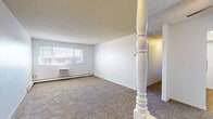 Located at 2300 E 18th St in Casper, Wyoming, this single-floor unit offers three bedrooms and one bathroom within a practical and functional layout. The carpeted living room is a welcoming open space accented by a ceiling fan, a textured ceiling, and a wall-unit air conditioner beneath a multi-pane window that lets in natural light. A decorative white baluster post serves as a subtle architectural detail near the entryway, which features a solid wood door. The living area flows directly into the galley-style kitchen, which is finished with warm wood cabinetry, white countertops, light hardwood-style flooring, and includes a range, refrigerator, dishwasher, and sink — all efficiently arranged for ease of use. A tray ceiling detail adds a touch of character to the kitchen. The three bedrooms are carpeted and well-proportioned, with the primary bedroom featuring a walk-in closet with built-in shelving. Additional bedrooms offer windows with natural light and baseboard heating. The bathroom is clean and straightforward, with a tiled tub-shower combination, wood-toned vanity, hardwood-style flooring, and an adjacent linen closet with wire shelving. Baseboard heating is present throughout the unit.