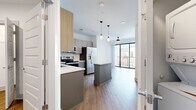 Located at 1001 16th Ave S in Nashville, TN, this two-bedroom, one-bathroom unit offers a well-designed layout across a single floor. The open-concept kitchen serves as a centerpiece, featuring two-tone cabinetry with light wood uppers and slate-blue lower cabinets, quartz countertops, a herringbone-patterned tile backsplash, and a full suite of stainless steel appliances including a French door refrigerator, electric range, built-in microwave, and dishwasher. A central kitchen island provides additional prep and seating space. Wood-look flooring runs throughout the unit, contributing to a cohesive, contemporary aesthetic. The living area extends toward a floor-to-ceiling glass sliding door that opens to a private balcony, allowing abundant natural light. The primary bedroom offers a comfortable footprint with a ceiling fan and dedicated closet space, while a second bedroom provides flexible use. Two closets, including a walk-in with wire shelving, add practical storage. The bathroom includes a soaking tub with marble-style tile surround, a quartz vanity with gray cabinetry, and wood-look flooring, maintaining the modern finishes found throughout the unit.
