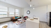 Located at 331 Park Central E St in the heart of Springfield, MO, this modern 2-bedroom, 2-bathroom unit offers a well-designed single-floor layout that maximizes every square foot. The open-concept living and kitchen area serves as the centerpiece of the home, where soaring ceilings and a bank of large windows flood the space with natural light and frame sweeping views of the surrounding cityscape. Sleek pendant lighting adds a contemporary touch overhead.

The kitchen is thoughtfully designed with crisp white cabinetry, light quartz countertops, a spacious island with bar seating, and a full suite of stainless steel appliances including a refrigerator, electric range, and microwave. Light wood-tone flooring flows throughout, tying the spaces together seamlessly.

Both bedrooms are bright and comfortable, each benefiting from natural light and access to closet storage. The primary bedroom offers a cozy, private retreat, while the second bedroom also features a sliding closet and ample room for a workspace. The two bathrooms are finished with clean, modern fixtures, including a glass-enclosed shower with marble-style tile surround. Additional conveniences include in-unit laundry, a hallway, and dedicated closet space — making this a fully functional and stylish urban residence.