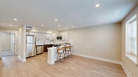 Located at 349 Chilton Ct in Plymouth Meeting, PA, this thoughtfully designed single-floor unit offers a clean, modern aesthetic throughout its two-bedroom, single-level layout. The open-concept kitchen and living area serves as the heart of the home, featuring a striking two-tone kitchen with white upper cabinetry, rich dark wood lower cabinets, a white subway tile backsplash, and a full suite of stainless steel appliances including a refrigerator, dishwasher, microwave, and range. A white peninsula with bar seating creates a natural division between the kitchen and the open living area, which is finished with light hardwood-style flooring and recessed lighting that brightens the entire space. The two bedrooms are carpeted for comfort and share a warm, neutral color palette. Each bedroom benefits from recessed lighting, and the primary bedroom includes a closet. A second closet is also available elsewhere in the unit. Natural light filters in through multiple windows fitted with blinds, with views of the surrounding neighborhood. The unit is further completed by a dedicated laundry area and a utility room, ensuring practical, everyday functionality. The overall design is clean, contemporary, and move-in ready.