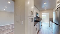 Located at 19143 Victory Blvd in Reseda, California, this thoughtfully renovated single-story residence showcases a clean, contemporary aesthetic throughout its well-appointed layout. The galley-style kitchen serves as a standout feature, outfitted with crisp white shaker cabinetry, brushed nickel hardware, dark quartz countertops, a subway tile backsplash, and a full suite of stainless steel appliances including a range, over-the-range microwave, and refrigerator. Light wood-style flooring runs throughout the main living areas and hallways, complemented by recessed lighting and crown molding that lend a polished finish to each room. The spacious living areas are bright and open, with neutral wall tones and large windows that allow natural light to fill the space. The bedrooms feature plush carpeting, plantation shutters for privacy and light control, ceiling fans, and mirrored sliding closet doors that enhance the sense of space. The bathrooms are cleanly designed with white shaker vanities, taupe countertops, oil-rubbed bronze fixtures, wood-look tile flooring, and frosted glass shower enclosures. A connecting hallway with overhead ventilation ties the layout together, providing a smooth and functional flow between all areas of the home.