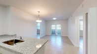 Located at 14981 SW 283 St in Homestead, FL, this single-story unit offers a clean, modern layout designed for comfortable living. The open-concept kitchen serves as the centerpiece of the main living area, featuring a peninsula with granite countertop and an integrated sink, light gray cabinetry, white appliances including a refrigerator, electric range, and microwave, and a walk-in pantry closet. A pendant light fixture above the peninsula adds a refined touch to the space.

The kitchen flows seamlessly into the living and dining areas, which are bathed in natural light from sliding glass doors fitted with vertical blinds. Light-toned large-format tile flooring extends throughout, creating a cohesive and airy feel. The living area provides direct outdoor access, enhancing the connection to natural light and ventilation.

The bedrooms are well-proportioned, each with the same light tile flooring and ample wall space. The electrical panel is conveniently integrated near the entry. The bathrooms are finished with granite-topped vanities, white cabinetry, large mirrors, and tub-shower combinations with tile surrounds. Clean white walls and recessed lighting throughout contribute to a bright, neutral palette that defines this well-appointed Homestead residence.