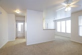 This single-floor residence offers a clean, functional layout designed for comfortable everyday living. The open living area is carpeted in neutral tones and benefits from abundant natural light streaming through multiple windows with horizontal blinds. A ceiling fan overhead provides air circulation, while a pass-through counter connects the living space to the kitchen, creating an open, communicative flow between the two areas. The kitchen is fully equipped with white cabinetry, laminate countertops, a coil-burner electric range, built-in microwave, and a refrigerator, providing all the essentials for meal preparation. The bedrooms are generously sized, each featuring plush carpeting, ceiling fans, and ample natural light. The primary bedroom includes a walk-in closet and direct access to its own bathroom, while additional bedrooms offer closet storage and easy access to shared spaces. The bathrooms are finished with tile flooring in an earthy stone pattern, white vanity cabinetry, laminate countertops, and a single-sink setup. The primary bath features a glass-enclosed shower. A dedicated laundry room houses a full-size washer and dryer set, finished with matching tile flooring and shelving for added storage convenience.