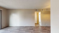 Located at 1605 Campbell Pkwy in Joplin, Missouri, this single-story unit offers a well-organized layout with a clean, updated interior throughout. Wood-look plank flooring runs consistently across the living areas and bedrooms, lending a cohesive and modern aesthetic to the space.

The living room serves as the focal point of the unit, featuring a wood-paneled fireplace surround and a full-width sliding glass door that floods the room with natural light and provides views of the surrounding exterior. A front entry door is conveniently positioned nearby. The textured popcorn ceiling is present throughout, adding a classic residential character.

An adjacent dining area is defined by a decorative chandelier overhead, creating a distinct and inviting space for meals. The kitchen is efficiently designed with gray cabinetry, light granite-style countertops, a stainless steel sink, and black appliances including a refrigerator and range, with additional storage provided by upper cabinets.

The bedroom features a ceiling fan with integrated lighting, a window with blinds offering outside views, and ample wall space. The bathroom is neatly appointed with a tub-shower combination, a vanity with granite-style countertops, wood-look tile flooring, and ventilation. Multiple HVAC vents are distributed throughout the unit for efficient climate control.