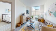 Located at 17–37 Huguenin Ave in Charleston, SC, this single-floor residence offers a thoughtfully designed layout with a clean, contemporary aesthetic throughout. Light wood-tone flooring flows continuously across the living areas, connecting each room with a cohesive, modern feel.

The kitchen is a standout feature, showcasing rich dark wood cabinetry that extends to the ceiling, full stainless steel appliances including a refrigerator, range, microwave, and dishwasher, granite countertops, a classic white subway tile backsplash, and a central island with pendant lighting overhead — ideal for both everyday cooking and entertaining.

The living area is bright and inviting, anchored by a large floor-to-ceiling window that allows abundant natural light to fill the space and offers views of the surrounding community. The room provides generous space for comfortable seating arrangements.

A well-proportioned hallway connects the living spaces to two separate bedrooms. The primary bedroom features dual floor-to-ceiling windows framing outdoor views, a ceiling fan, and warm, neutral finishes. The secondary bedroom mirrors this bright, airy character with its own large window and ceiling fan.

Throughout the residence, the white walls, natural light, and consistent flooring create a calm, contemporary ambiance well suited to the vibrant Charleston, SC location.