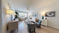 Located at 100 Harley Ln in Pooler, Georgia, this single-floor residence offers a well-appointed layout designed for comfortable, modern living. The open-concept living room is bright and welcoming, featuring light wood-style flooring, a ceiling fan, and large windows that invite natural light. A coastal-inspired color palette of soft whites, warm neutrals, and aqua accents creates a calm, cohesive ambiance throughout.

The kitchen is a functional centerpiece, outfitted with gray shaker-style cabinetry, granite countertops, a white subway tile backsplash, and a full suite of stainless steel appliances. A central island with seating provides additional prep space and casual dining options, while pendant and track lighting add a contemporary touch.

The bedroom offers a tranquil retreat with wood-style flooring, warm lighting, and tasteful décor. Two bathrooms serve the residence — one featuring a granite-topped vanity and shower, and the other offering a full soaking tub and tub-shower combination, both finished with gray cabinetry and polished chrome fixtures.

The property also includes access to shared community spaces, including a bright gathering room with large windows and pendant lighting, as well as a billiards room with views of the outdoors — ideal for recreation and socializing.
