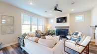 This thoughtfully designed two-story home blends modern aesthetics with functional living across both levels. The main floor opens with a stylish entryway featuring a sleek barn door with matte black hardware, leading into bright, open living spaces finished with durable hardwood-style flooring throughout. The living room is a standout, offering large windows that flood the space with natural light, a ceiling fan, a wall-mounted television, and a contemporary fireplace framed by clean-lined millwork. The kitchen is equipped with white shaker cabinetry, bold dark granite countertops, a classic subway tile backsplash, and stainless steel appliances including a gas range and built-in microwave. A dedicated office on the main level features hardwood-style flooring and ample natural light, ideal for remote work or meetings. Upstairs, plush carpet carries through the bedrooms and a spacious walk-in closet with wire shelving systems provides generous storage. Additional bedrooms and a full bathroom with a tub-shower combination and tile flooring round out the upper level. A dedicated laundry room with a window, tile flooring, and top-loading washer and dryer adds everyday convenience. Throughout, neutral tones, recessed lighting, and consistent matte black hardware create a cohesive, contemporary feel.