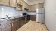 Located at 130 Columbia St W in Waterloo, Ontario, this 2-bedroom, 1-bathroom unit offers a thoughtfully designed layout across a single floor. Light wood-style flooring runs throughout, lending a clean and contemporary feel to the entire space.

The kitchen is a functional highlight, featuring a two-tone cabinetry scheme with light upper cabinets and rich dark lower cabinets, granite-style countertops, a tiled backsplash, and a full suite of black appliances including a refrigerator, electric range, and dishwasher — providing everything needed for everyday cooking.

The primary bedroom is a comfortable space with a built-in closet offering wire shelving and hanging storage. The second bedroom benefits from natural light through a large window with views of surrounding greenery, creating a bright and pleasant atmosphere. Both rooms feature the same light flooring consistent with the rest of the unit.

The bathroom is finished in neutral grey tones with large-format floor tiles, a standalone walk-in shower with built-in shelving, and clean white fixtures complemented by brushed nickel hardware.

Overall, the unit presents a modern, neutral aesthetic with practical finishes, making it a well-suited space for students or young professionals in the Waterloo area.
