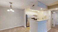 Located at 222 Old Fayetteville Rd in Carrboro, NC, this single-floor residence offers a thoughtfully designed layout with a comfortable, functional flow throughout. The open-concept living and dining area is generously sized, featuring neutral-toned carpet, a ceiling fan with light fixture, and a sliding glass door that opens to a private balcony with outdoor views, filling the space with natural light. A stylish chandelier accents the dining area, adding a warm touch.

The kitchen is efficiently designed with a galley-style layout, featuring wood-look flooring, white cabinetry, granite-style countertops, stainless steel appliances including a refrigerator and electric range, a built-in dishwasher, and a peninsula that opens toward the living area. Track lighting overhead provides bright, focused illumination throughout the kitchen.

The bedrooms are carpeted and bathed in natural light from large windows with blinds, offering a calm and restful atmosphere. The bathroom is finished with a classic black-and-white checkered tile border along the tub surround, lending a timeless, crisp aesthetic. A textured ceiling is consistent throughout the home, complementing the neutral wall tones that create a clean, move-in-ready feel.