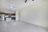 Located at 917 NW 97th Ave, Unit 301, in Miami, FL, this 780-square-foot, two-bedroom, one-bathroom condominium is situated on the third floor of a Mediterranean-style residential community. The unit's layout includes a kitchen, two bedrooms, a full bathroom, a hallway, a dedicated laundry room, and a closet.

The kitchen is a standout feature, designed with rich wood-grain cabinetry, dark granite countertops, and a central island that provides additional workspace and storage. Stainless steel appliances — including a French-door refrigerator, electric range, built-in microwave, and dishwasher — complete the space, while white tile flooring and under-cabinet lighting contribute to a clean, modern aesthetic.

Both bedrooms feature neutral carpet flooring and windows fitted with horizontal blinds that allow for adjustable natural light. The primary bedroom measures 140 square feet. The shared bathroom includes a tiled soaking tub and shower combination, a wood-grain vanity with granite countertop, and white tile flooring. The dedicated laundry room houses a full-size washer and dryer.

A private balcony, accessible through an arched opening, overlooks the surrounding community and tree-lined grounds.