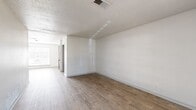 Located at 6555 Lexington Dr in Beaumont, TX, this single-story 2-bedroom, 1-bathroom home offers a practical and well-organized layout across a comfortable footprint. The interior features warm wood-look flooring throughout the main living areas, hallway, kitchen, and bathroom, while the bedrooms are finished with neutral carpet for a softer feel.

The two living areas provide flexible spaces for lounging or dining, with white walls and natural light streaming through window blinds creating a bright, clean atmosphere. Textured ceilings add a classic touch seen consistently throughout the home.

The kitchen is efficiently designed in a galley-style configuration, featuring rich dark brown cabinetry, granite-look countertops, and black appliances including an electric range, dishwasher, and refrigerator. Ample cabinet storage lines both sides of the kitchen, maximizing functionality.

Both bedrooms are well-proportioned with carpet flooring, white walls, and good natural light. The primary bedroom offers a generous amount of space. The bathroom includes a full tub/shower combo with white tile surround, dark wood vanity cabinetry, granite-look countertops, and overhead storage. A dedicated closet and hallway complete the layout, with a paneled front entry door welcoming residents into the home.