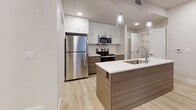 Located at 2233 North Records Way in Meridian, Idaho, this well-appointed single-floor residence offers a clean, contemporary design throughout. The open living area is finished with light wood-tone flooring, recessed lighting, and a ceiling fan, creating a bright and comfortable atmosphere. Large windows allow natural light to filter in, offering views of the surrounding community landscape.

The modern kitchen is a standout feature, equipped with stainless steel appliances including a refrigerator, electric range, and microwave. Two-tone cabinetry pairs white upper cabinets with warm wood-finish lower cabinets, complemented by a white countertop island with an undermount sink and stylish pendant lighting above — ideal for both cooking and casual dining.

The bedrooms are carpeted for warmth and comfort, each benefiting from natural light through well-sized windows. One bedroom includes direct access to a walk-in closet area, adding practical storage. A dedicated linen or storage closet with multiple shelves provides additional organization throughout the unit.

The bathroom features a spacious glass-enclosed shower with built-in shelving, a bench seat, and chrome fixtures, offering a clean and accessible design. A thoughtful layout and neutral color palette throughout tie the space together with a polished, move-in-ready feel.