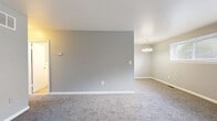 Located at Purdue Ave in Baltimore, MD, this single-floor, one-bedroom, one-bathroom residence offers a practical and well-organized layout. The combined living and dining area forms the heart of the home, featuring soft gray walls, plush wall-to-wall carpeting, and a decorative chandelier that anchors the dining space. A central dividing wall defines the flow between the living area and the kitchen corridor, which showcases warm wood cabinetry offering ample storage and workspace. The bedroom is a comfortable, carpeted retreat with a window fitted with blinds that allow natural light to filter in. It includes a built-in closet complete with multiple shelving tiers and a hanging rod, providing excellent organization. In total, the unit features three closets, ensuring generous storage throughout. The full bathroom is finished with neutral tile flooring, white tile surround on the tub-shower combo, and a wood-toned vanity, creating a clean and functional space. A hallway connects the main living areas to the private spaces, maintaining a logical and efficient floor plan. The consistent gray color palette, white trim, and carpeted floors throughout lend the unit a cohesive, move-in-ready aesthetic.