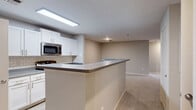 Located at 1000 Cameron Woods Dr in Apex, NC, this single-floor, 3-bedroom, 2-bathroom home offers a well-organized layout designed for comfortable everyday living. The open-concept kitchen, dining, and living area forms the heart of the home. The kitchen is outfitted with white cabinetry, subway tile backsplash, dark countertops, stainless steel appliances including a gas range, built-in microwave, and refrigerator, plus light wood-look flooring and a dedicated walk-in pantry with wire shelving. A peninsula countertop provides additional workspace and opens seamlessly to the living and dining areas. The spacious living room features soft carpeting, a ceiling fan with light, and a glass door leading to an outdoor balcony, allowing natural light and greenery views to fill the space. The three bedrooms are carpeted and well-sized, each offering closet storage. The primary bedroom includes its own closet. Both bathrooms are finished with white cabinetry, dark countertops, and tile surround tub/shower combinations set over wood-look flooring. Additional conveniences include a dedicated laundry room, utility room, pantry, and ample closet space throughout, making this a highly functional and move-in-ready home.